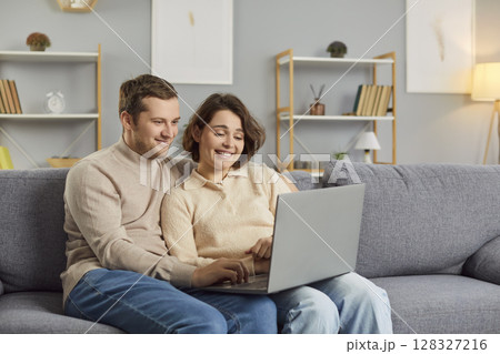 Couple enjoy spending free time together at home surf internet via laptop Couple enjoy spending free time together at home surf internet via laptop 128327216