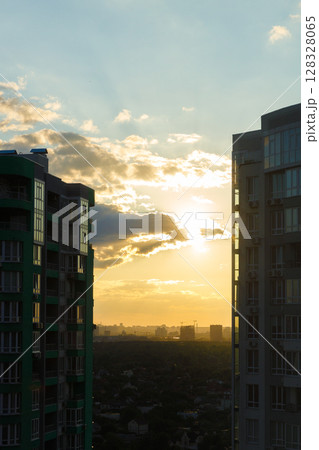 Stunning Sunset Over a Cityscape with Tall Buildings Framing the Golden Horizon and Cloud Patterns that Create a Serene Atmosphere in an Urban Environment 128328065