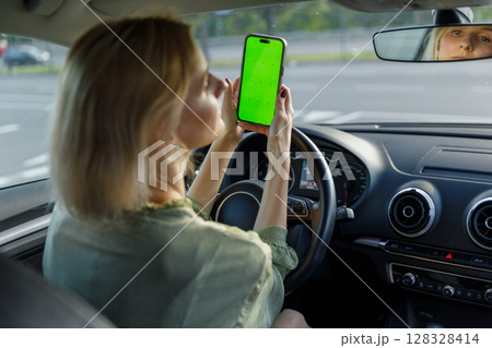 Woman in a Car Holding a Smartphone with Green Screen While Driving: A Glimpse Into Multi-tasking and Technology's Role in Modern Commuting Woman in a Car Holding a Smartphone with Green Screen While Driving: A Glimpse Into Multi-tasking and Technology's Role in Modern Commuting 128328414