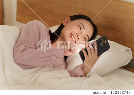 夜ベッドでスマホを使う女性 128328749