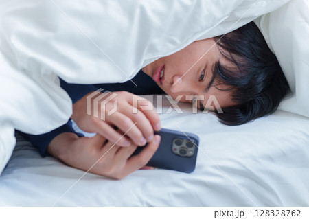 ベッドでスマホを使う男性 128328762