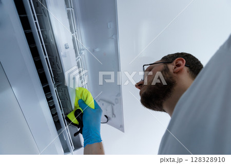A person thoroughly cleaning an air conditioning unit, ensuring optimal performance and hygiene by removing dust and debris effectively and safely using the right tools and techniques. 128328910