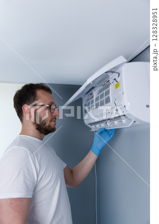 Technician Performing Maintenance on Air Conditioning Unit: Importance of HVAC Service for Home Comfort, Efficiency and Clean Air Quality in Residential Spaces 128328951
