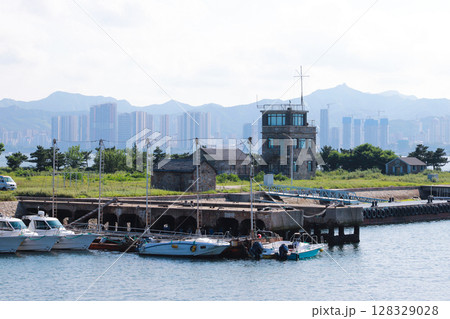 Scenic Harbor View with Boating Activity Surrounded by Majestic Mountains and Modern City Skyline, Showcasing a Blend of Nature and Urban Life in the Background 128329028