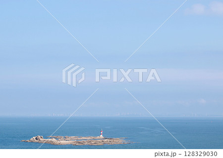 A Serene Coastal Landscape Featuring a Striking Lighthouse on a Rocky Island Surrounded by Expansive Ocean Waters and a Clear Blue Sky A Serene Coastal Landscape Featuring a Striking Lighthouse on a Rocky Island Surrounded by Expansive Ocean Waters and a Clear Blue Sky 128329030