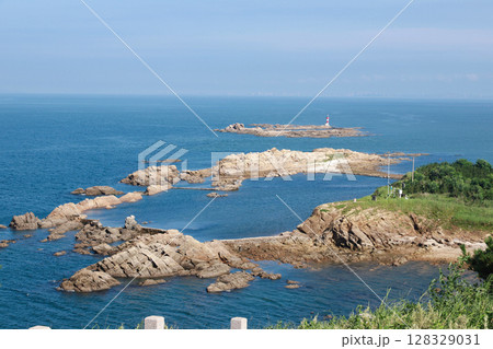 Stunning Coastal View Featuring Rocky Outcrops and a Lighthouse Against a Clear Blue Sky and Serene Ocean Landscape Stunning Coastal View Featuring Rocky Outcrops and a Lighthouse Against a Clear Blue Sky and Serene Ocean Landscape 128329031