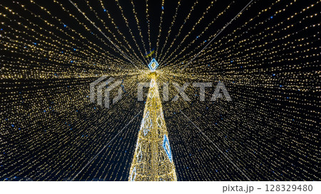 A Stunning Display of Holiday Lights Creating a Magical Atmosphere Above a Beautifully Decorated Tree for Festive Celebrations During the Night Sky 128329480