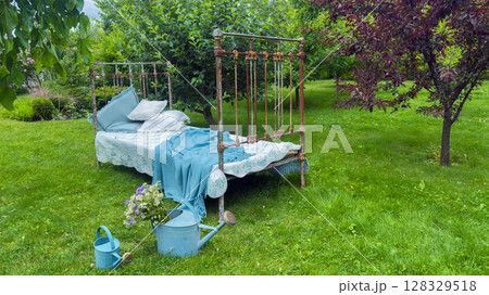 Charming Outdoor Scene Featuring a Vintage Bed Surrounded by Lush Greenery and Colorful Flowers, Perfect for Relaxation in a Peaceful Garden Setting Charming Outdoor Scene Featuring a Vintage Bed Surrounded by Lush Greenery and Colorful Flowers, Perfect for Relaxation in a Peaceful Garden Setting 128329518