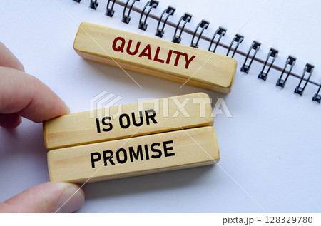 Quality Is Our Promise text on wooden blocks over notebook conveys commitment backed by meaningful intent Quality Is Our Promise text on wooden blocks over notebook conveys commitment backed by meaningful intent 128329780