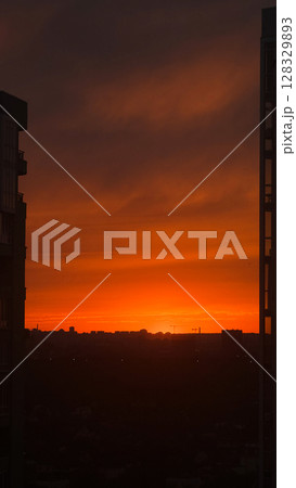 Stunning Urban Sunset Showcasing an Orange Glow with Silhouetted Buildings Against the Vibrant Evening Sky, Capturing the Essence of a Peaceful Twilight Moment Stunning Urban Sunset Showcasing an Orange Glow with Silhouetted Buildings Against the Vibrant Evening Sky, Capturing the Essence of a Peaceful Twilight Moment 128329893