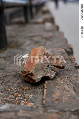 A Singular Fragment: The Beauty of a Weathered Brick Piece Set Against an Urban Landscape and Stone Pathway Captures the Essence of Time and Nature's Erosion in an Artistic Way A Singular Fragment: The Beauty of a Weathered Brick Piece Set Against an Urban Landscape and Stone Pathway Captures the Essence of Time and Nature's Erosion in an Artistic Way 128330200