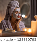 Evening Self-Care Routine with Face Mask and Candlelight. A serene and intimate moment of evening self-care, featuring a woman gently applying a face mask in a softly lit room. Surrounded by 128330793