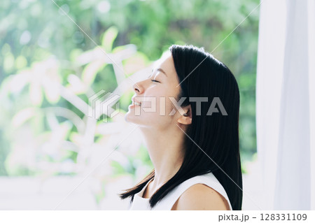 窓辺に立つ若い女性のポートレート 128331109