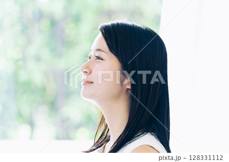 窓辺に立つ若い女性のポートレート 128331112