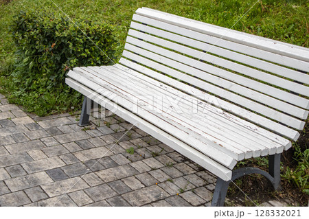 White wooden park bench against lush green nature in a quiet park, side view 128332021