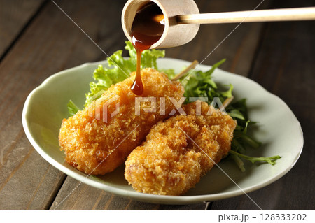 敷いた野菜とソースがかかった串カツ 128333202