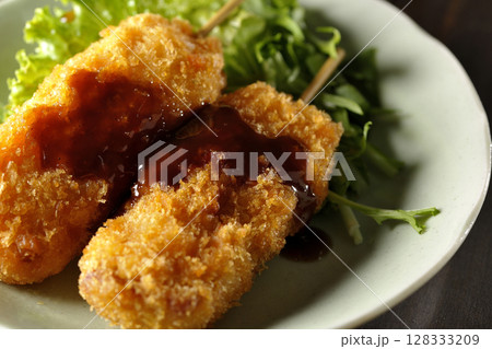 敷いた野菜とソースがかかった串カツ 128333209