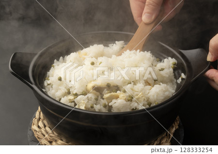 炊き上がった湯気の立つ実山椒の炊き込みご飯を混ぜて茶碗に盛り付ける 炊き上がった湯気の立つ実山椒の炊き込みご飯を混ぜて茶碗に盛り付ける 128333254