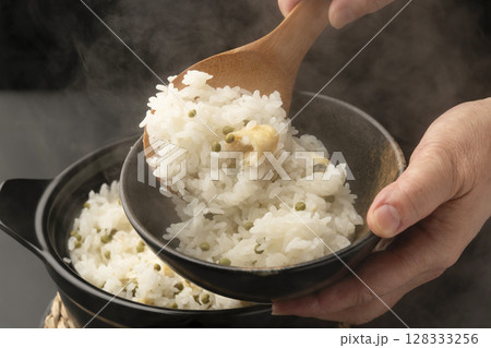 炊き上がった湯気の立つ実山椒の炊き込みご飯を混ぜて茶碗に盛り付ける 128333256
