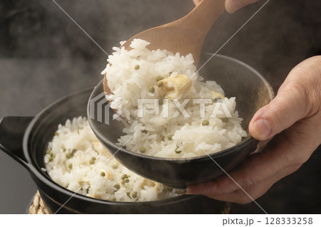 炊き上がった湯気の立つ実山椒の炊き込みご飯を混ぜて茶碗に盛り付ける 128333258