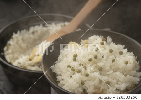 炊き上がった湯気の立つ実山椒の炊き込みご飯を混ぜて茶碗に盛り付ける 炊き上がった湯気の立つ実山椒の炊き込みご飯を混ぜて茶碗に盛り付ける 128333260