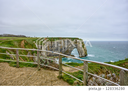Etretat cliff arch seen from coastal trail with railing 128336280