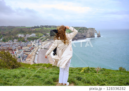 Windy day at Etretat with woman in white trench coat Windy day at Etretat with woman in white trench coat 128336282