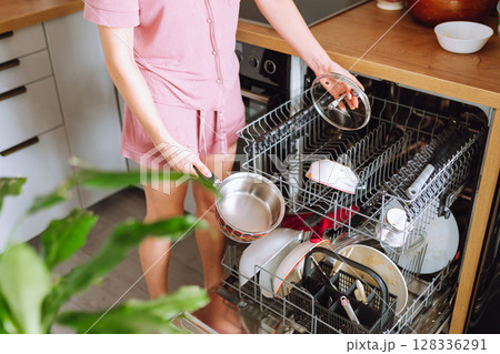 young woman using dishwasher in home kitchen young woman using dishwasher in home kitchen 128336291