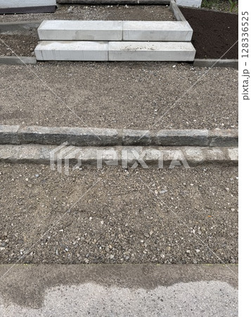 Gray and white staircase is on a gravel surface 128336525