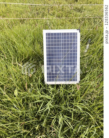 Solar panel is sitting on a grassy field Solar panel is sitting on a grassy field 128336562