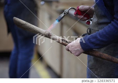 Man is holding a wooden stick with a flame on it 128336571