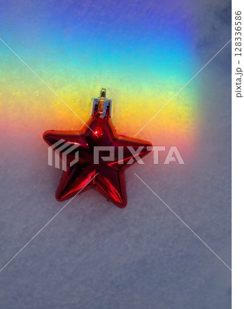 Red star ornament is sitting on top of a snowy surface 128336586