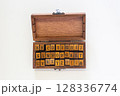 Handcrafted wooden box containing complete alphabet rubber stamps with uppercase letters and punctuation marks, arranged in three neat rows. Perfect for crafting, journaling, and traditional printing  128336774