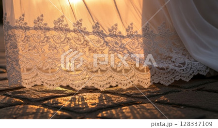 Delicate Ivory Lace Fabric Illuminated by Golden Sunset Light Cascading over Textured Surface 128337109