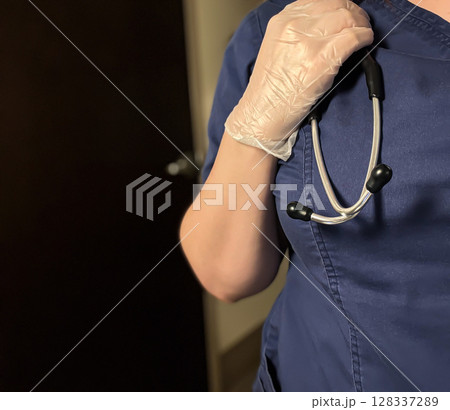 Healthcare Worker in Scrubs Holding Stethoscope While Wearing Gloves Healthcare Worker in Scrubs Holding Stethoscope While Wearing Gloves 128337289