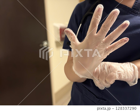 Nurse in Scrubs Putting on Medical Gloves Before Patient Care Nurse in Scrubs Putting on Medical Gloves Before Patient Care 128337290