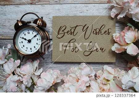 Best Wishes For You text with alarm clock and flowers decoration on wooden background 128337364