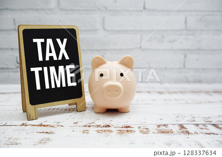 Tax Time text message and piggy saving on wooden and white brick wall background (Business concept) Tax Time text message and piggy saving on wooden and white brick wall background (Business concept) 128337634