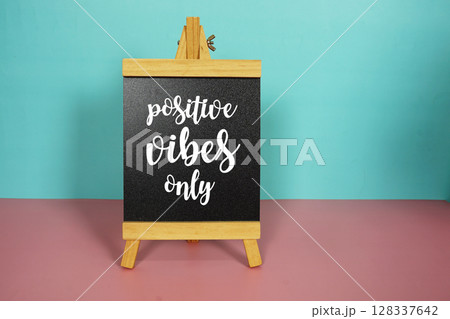 Positive vibes only text message on easel stand on pink and blue background Positive vibes only text message on easel stand on pink and blue background 128337642