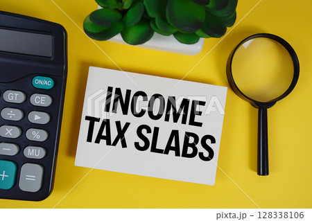 Income Tax Slabs text with magnifying glass anc calculator on yellow background Income Tax Slabs text with magnifying glass anc calculator on yellow background 128338106