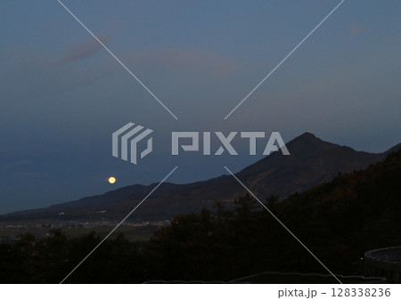 夜明け前、磐梯山の裾野に光る満月。シルエットの磐梯山と暗い青空に印象的で綺麗だ。 128338236