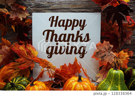 Happy Thanksgiving text message with pumpkins and maple leaf decoration on wooden background Happy Thanksgiving text message with pumpkins and maple leaf decoration on wooden background 128338364