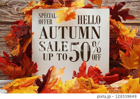 Autumn Sale 50% off text with maple leaf decoration on wooden background Autumn Sale 50% off text with maple leaf decoration on wooden background 128339649