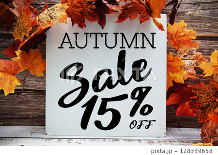 Autumn Sale 15% off text with maple leaf decoration on wooden background 128339658