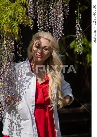 Wisteria Woman Portrait: Spring day, smiling lady poses in the garden during flowering season. 128340330