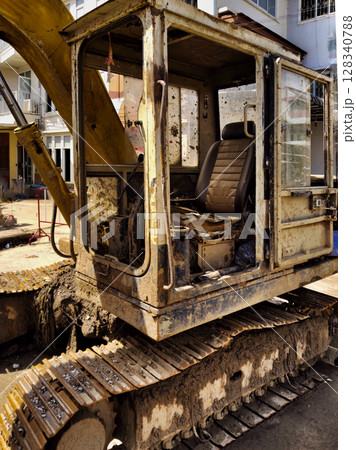 An excavator covered in mud after flood relief efforts after water receded 128340788