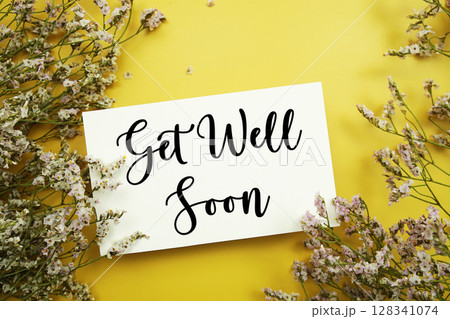 Get Well Soon text with flowers decoration on yellow background Get Well Soon text with flowers decoration on yellow background 128341074