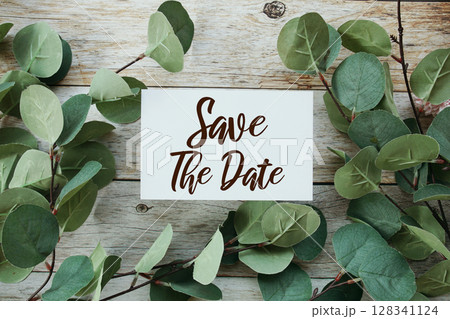 Save the Date text message with artificial green Eucalyptus leaf decoration on wooden background Save the Date text message with artificial green Eucalyptus leaf decoration on wooden background 128341124