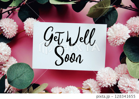 Get Well Soon text with flowers decorations on pink background 128341655