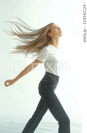 Confident Young Woman, with Flowing Hair, Gracefully Walking in a Bright Studio Environment Confident Young Woman, with Flowing Hair, Gracefully Walking in a Bright Studio Environment 128342124